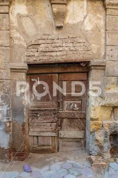 Broken wooden door on grunge stone bricks wall in abandoned street Stock Photos