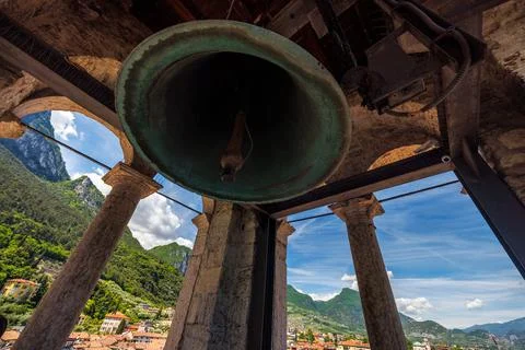 A bronze bell hangs from a stone structure, offering breathtaking views of ro Stock Photos