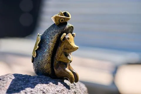 Bronze decorative figurine hedgehog with mouse hat sitting on rock outdoors.. Stock Photos