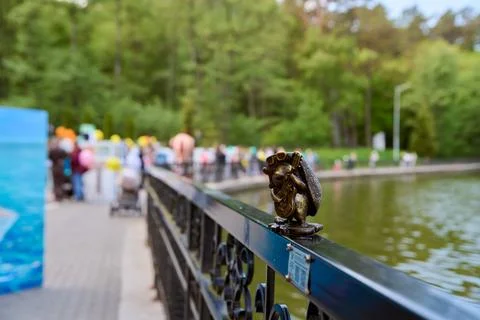 Bronze frog lock attached to park railing beside pond Stock Photos