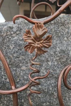 Bronze grape leaf and vine decoration on a grey stone wall surface Stock Photos