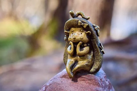 Bronze hedgehog figurine with worm on head sitting on rock outdoor soft foc.. Stock Photos