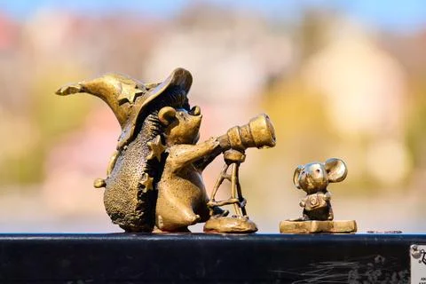 Bronze hedgehog statue with wizard hat using telescope near small mouse fig.. Stock Photos