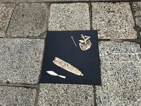 Bronze pavement plaque with engraved artifacts set in cobblestone sidewalk .. Stock Photos
