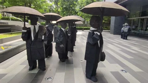 Bronze sculpture of men holding umbrellas in Singapore Stock Footage