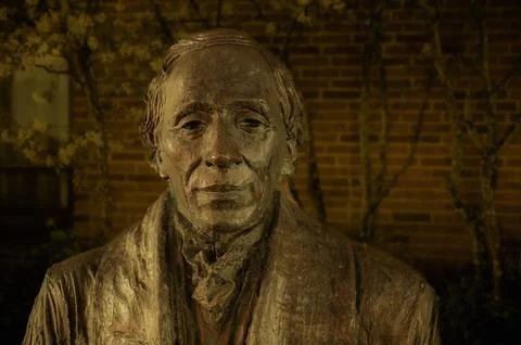 Bronze statue of H C Andersen against a brick wall Stock Photos