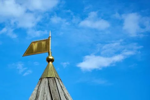 Bronze tip in the form of a flag on a pointed wooden roof against the sky Stock Photos