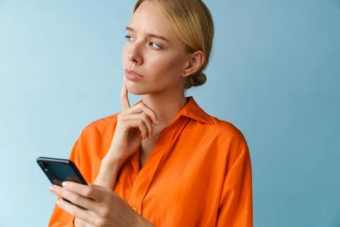 Brooding beautiful blonde girl using mobile phone and thinking Fotos de archivo