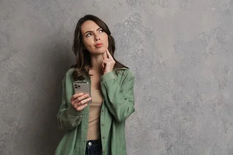 Brooding beautiful girl thinking while using cellphone Fotos de archivo