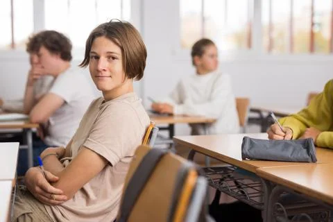 Brooding boy stands in a school class against background of classmates Stock Photos