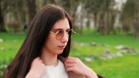 A brooding brunette lady sits at a park. Young girl in coat thought about Stock Footage 152112301