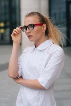 A brooding doctor with glasses in a white robe. Woman doctor the background o Stock Photos