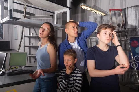 Brooding family tries to find a solution to a puzzle in a quest room Stock Photos
