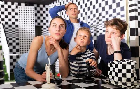 Brooding family trying to find a solution to a puzzle in the quest room Stock Photos