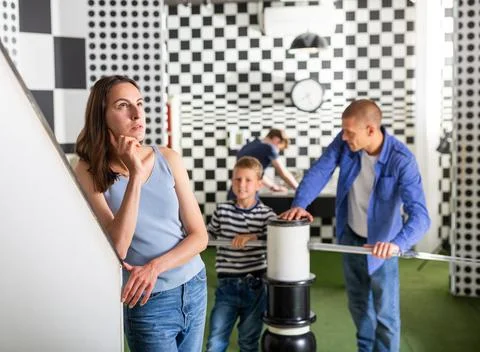 Brooding family trying to find a solution to a puzzle in the quest room Stock Photos