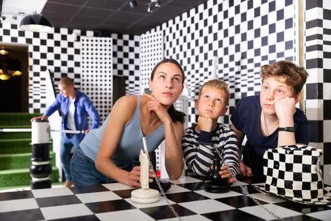 Brooding family trying to find a solution to a puzzle in the quest room Stock Photos