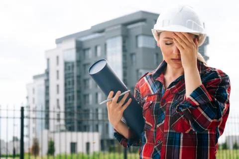 A brooding female builder with drawings of papers in her hands. Stock Photos