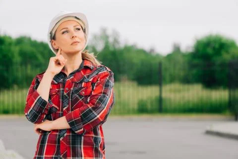 A brooding female builder with drawings of papers in her hands. Stock Photos