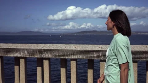 A brooding girl in her thoughts walks along the embankment along the ocean. Stock Footage 214660531