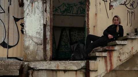 Brooding girl lies on the steps of an abandoned pier with graffiti Stock Footage 114623121