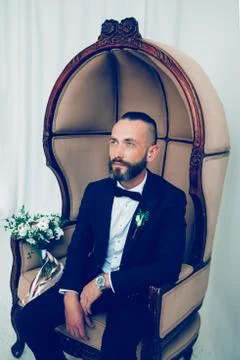 Brooding groom waiting for his bride sitting in a chair Stock Photos