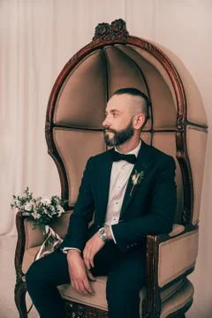 Brooding groom waiting for his bride sitting in a chair Stock Photos