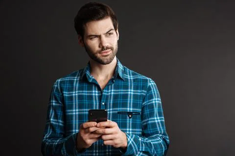Brooding handsome guy looking aside and using cellphone Stock Photos