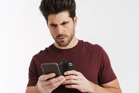 Brooding handsome man drinking coffee while using mobile phone Stock Photos