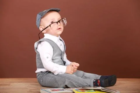 Brooding kid sitting on the floor in glasses with books Stock Photos