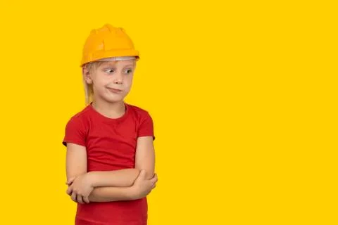 Brooding little boy in an orange helmet on yellow background. Choice of profe Stock Photos