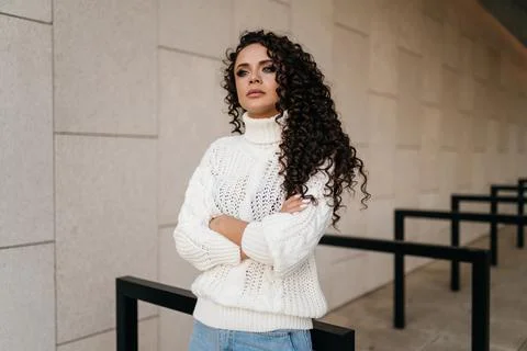 Brooding look and arms crossed on her chest by a curly brunette against the Stock Photos
