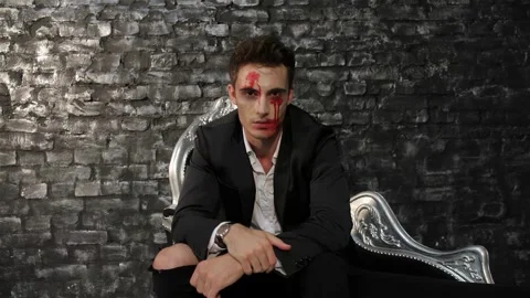 Brooding male vampire exuding dark charisma on a sleek black sofa Stock Footage 311189758