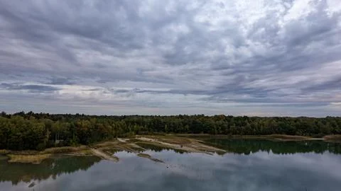Brooding Sky Over a Still Lake and Lush Forest Landscape Stock Photos