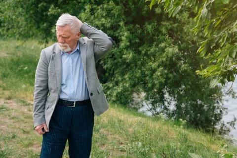 A brooding stylish old man in a business suit against the background of the f Stock Photos