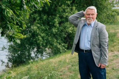 A brooding stylish old man in a business suit against the background of the f Stock Photos