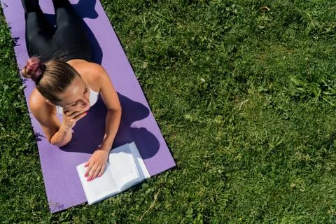 A brooding young girl with a book view from above, a sporty woman lies on a y Stock Photos