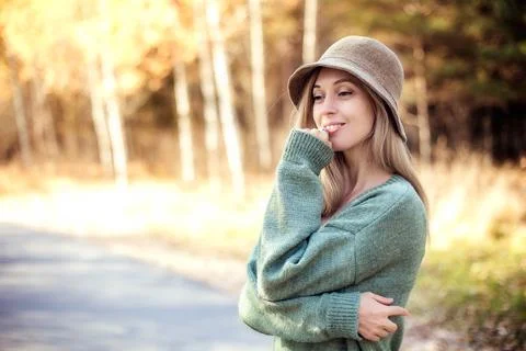 Brooding young girl in a hat and a green dress on a walk in an autumn park Stock Photos