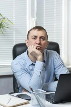 Brooding young man in the office behind the workplace. Portrait of an office  Stock Photos