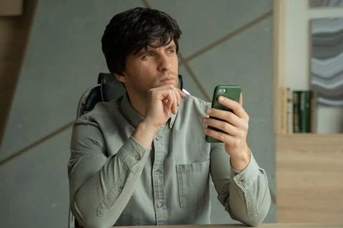 Brooding young man working in a modern studio-office. A person using a Stock Photos