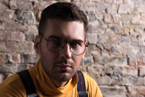 Brooding young trendy guy with stubble and glasses Stock Photos