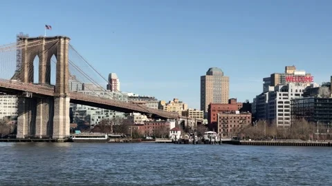 Brooklyn Bridge American flag waving over East River with BK welcome sign NYC Stock Footage 150812629