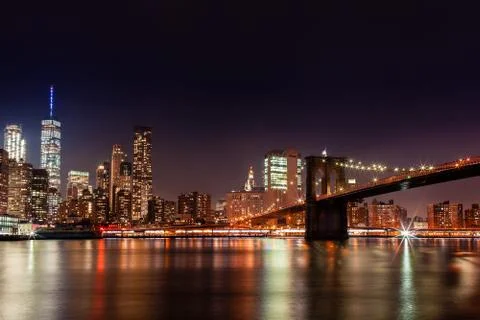 Brooklyn Bridge in the evening with midnight blue sky and smooth water surf.. Stock Photos