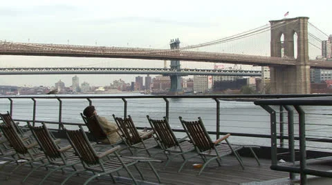 Brooklyn Bridge, man in deck chair at Pier 17 Video stock 24654095