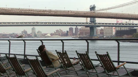 Brooklyn Bridge, man in deck chair at Pier 17 #2 Stock Footage 24697142