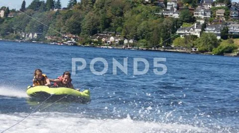 A brother and sister being pulled on an inner tube behind a boat, Seattle. Stock Photos