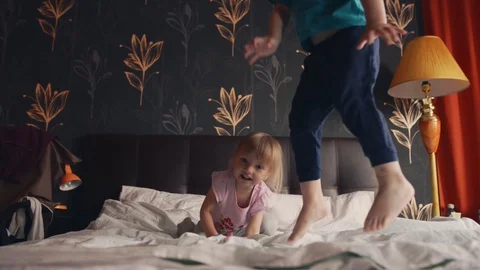 Brother and sister bouncing on double bed in their parents bedroom Stock Footage 124271403