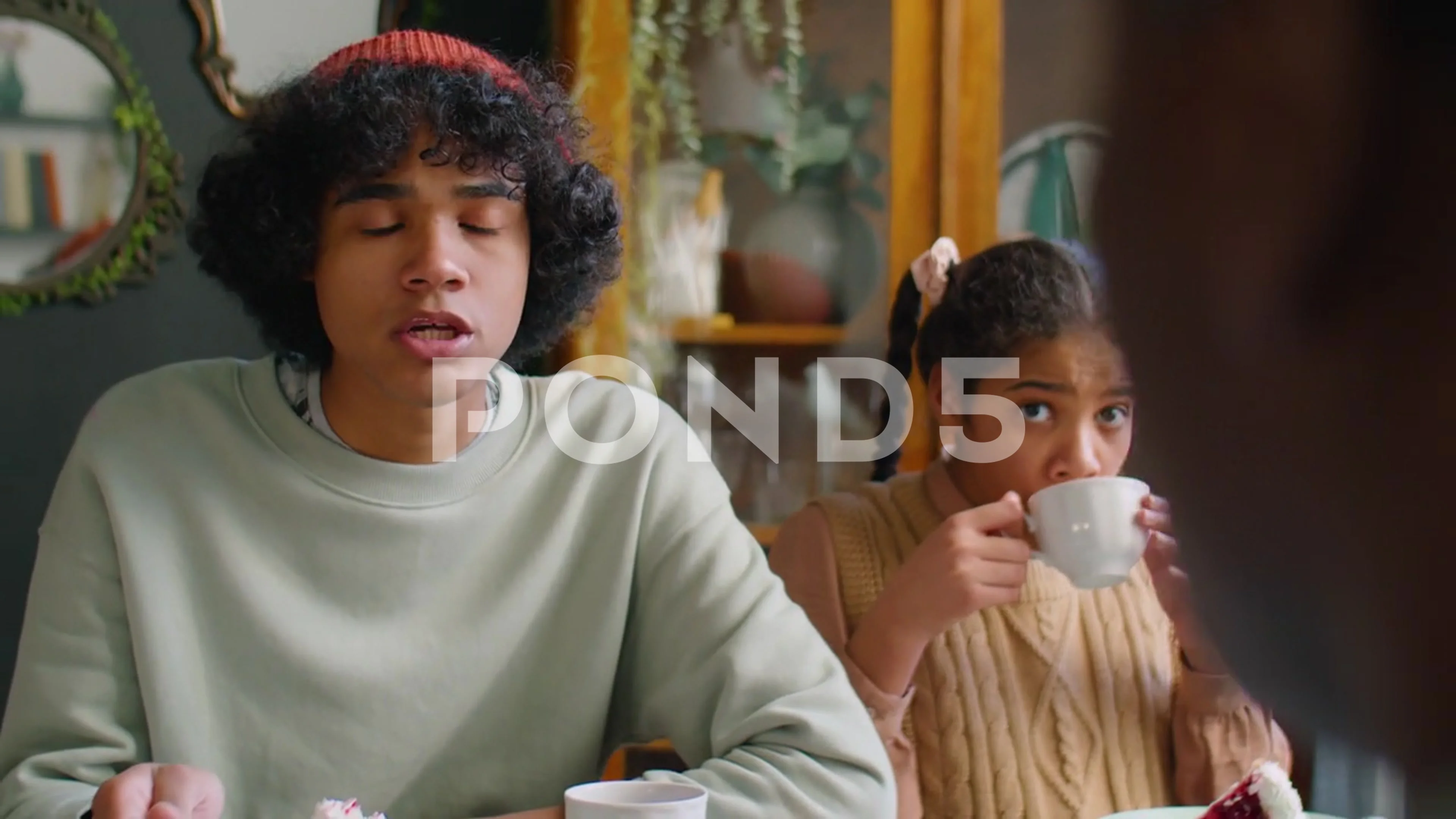 Brother and Sister Eating Cake and Chatting with Family at Dinner