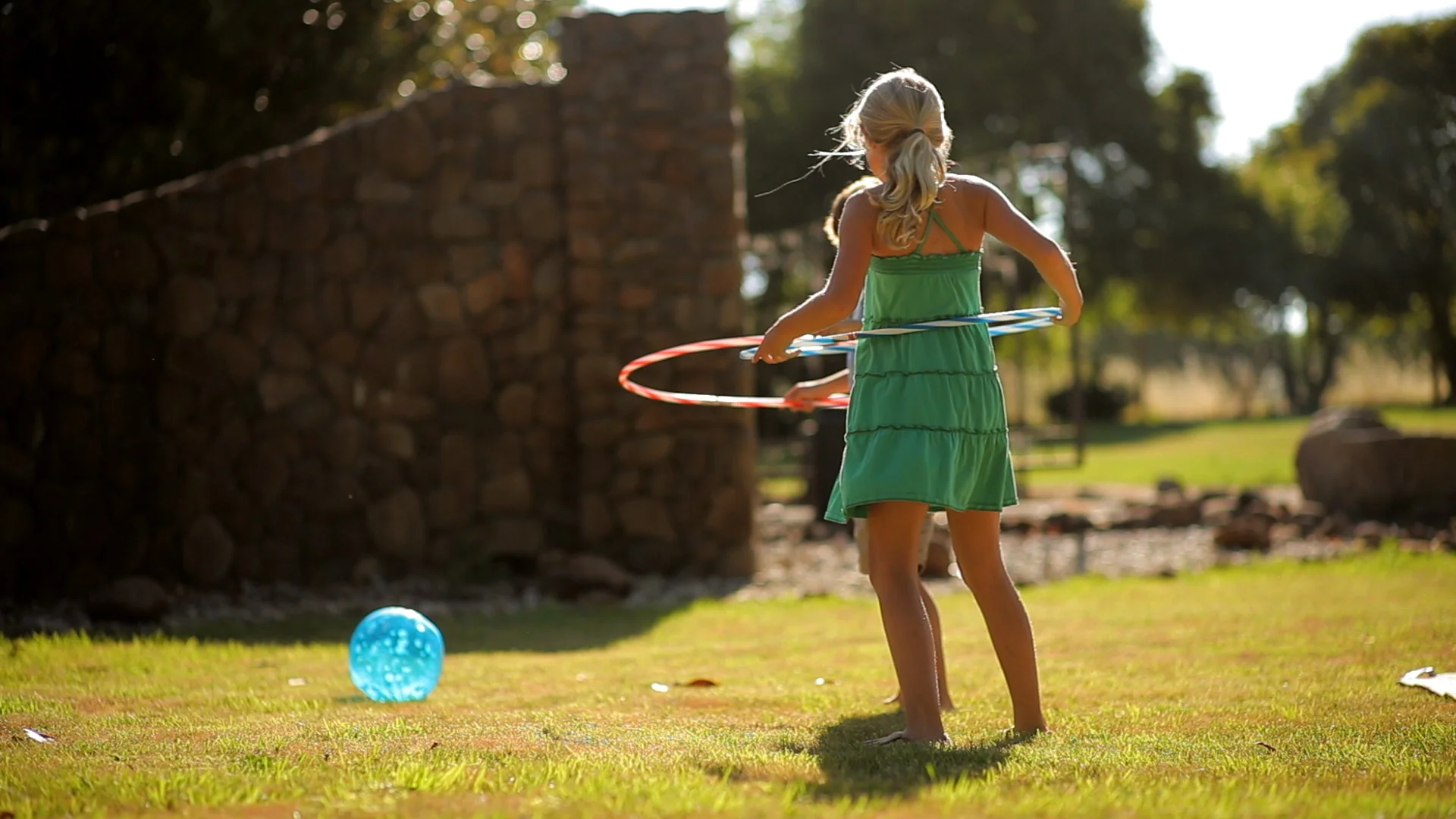 Brother and sister having fun playing with hula hoops in a sunny park.