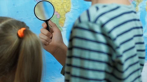 Brother and sister  learning a map through a magnifying glass, slow motion Stock Footage 121051371