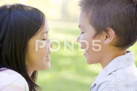Brother and sister outdoors staring at each other and smiling Stock-Fotos